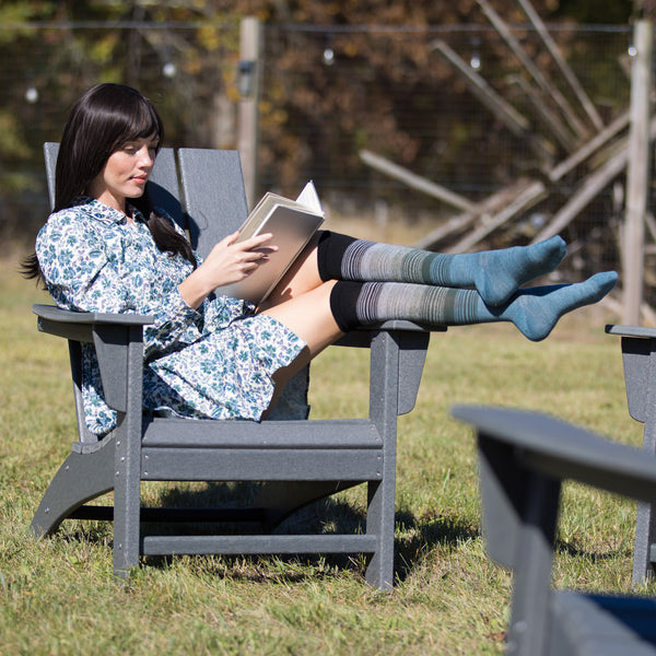 Woman reading a book in a gray chair outdoors work