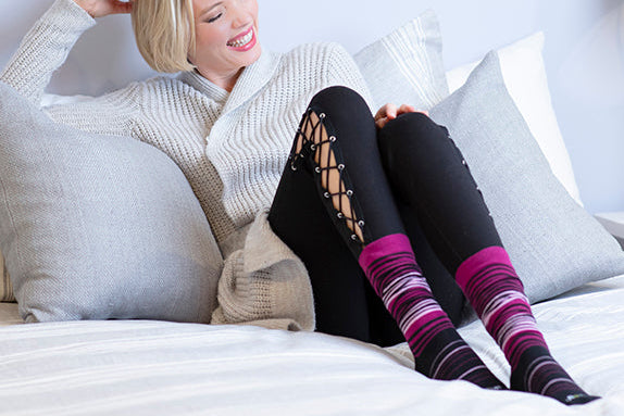 Woman sitting on a bed wearing patterned knee-high socks